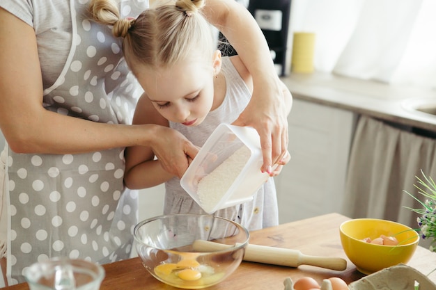 La bambina carina aiuta la mamma a cuocere i biscotti in cucina. Famiglia felice. Tonificante.