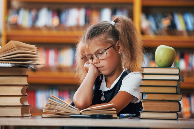 La bambina carina con le trecce è in biblioteca