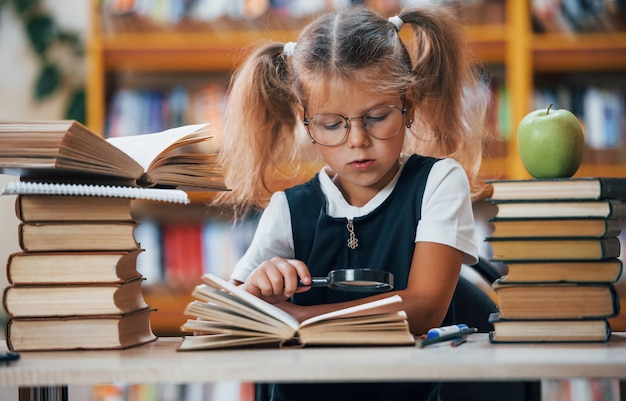 La bambina carina con le trecce è in biblioteca