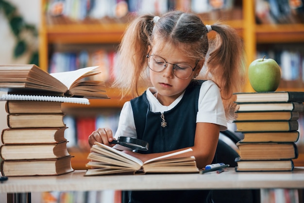 La bambina carina con le trecce è in biblioteca