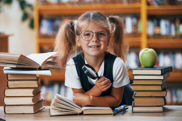 La bambina carina con le trecce è in biblioteca