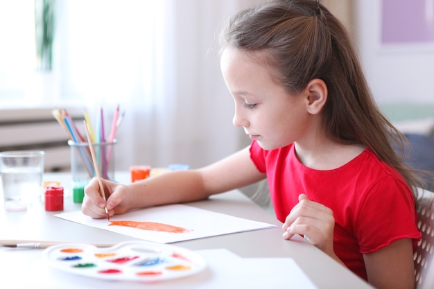 La bambina carina disegna i colori a casa