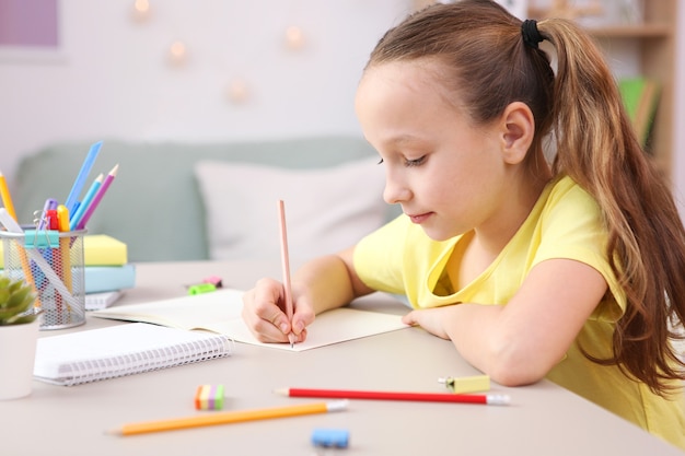 La bambina carina sta facendo i compiti all'interno della stanza