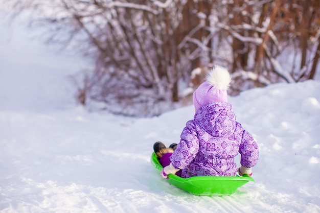 La bambina carina tira una slitta in una calda giornata invernale