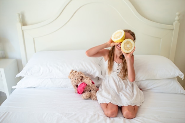 La bambina che copre gli occhi di metà del limone si avvicina agli occhi