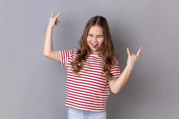 La bambina che mostra il segno del metallo pesante di gesto di rock and roll gode della musica preferita si diverte