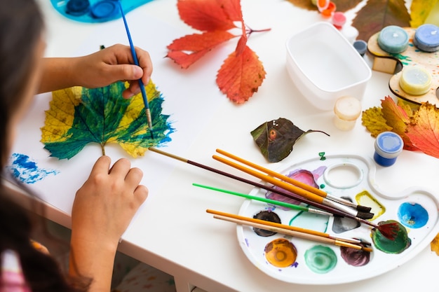 la bambina colora le foglie d'autunno a casa