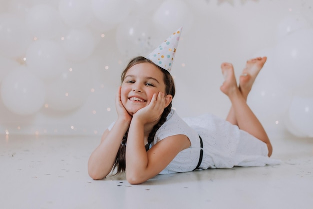 La bambina con due trecce in un vestito bianco festeggia il suo compleanno