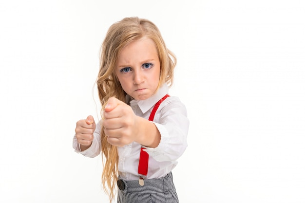 La bambina con i capelli biondi è arrabbiata e mostra un pugno