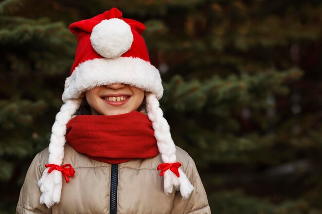 La bambina con il cappello di Natale se l'è tirato sugli occhi e ha riso di una bambina divertente di Capodanno
