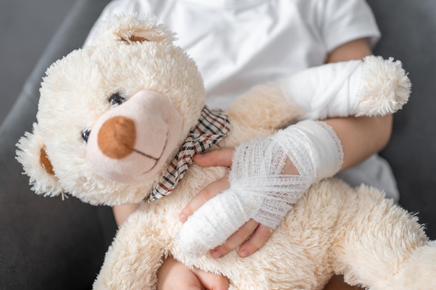 La bambina con il dito rotto tiene l'orsacchiotto con una zampa bendata all'appuntamento del medico in ospedale