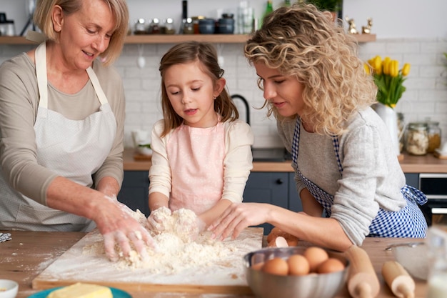 La bambina con la mamma e la nonna che fanno l'impasto