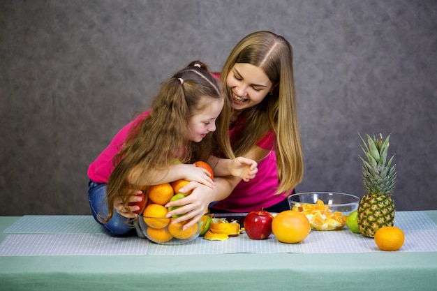 La bambina con la mamma gioca con la frutta e sorride. Vitamine e alimentazione sana per i bambini.