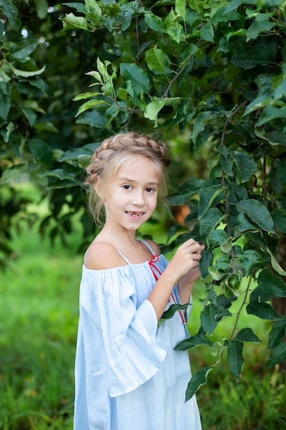 La bambina con un codino in testa vale nel meleto. Il bambino cammina nel bosco in primavera. Vacanze estive.