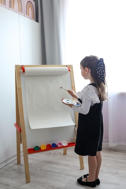 La bambina con una tavolozza in mano disegna su un cavalletto