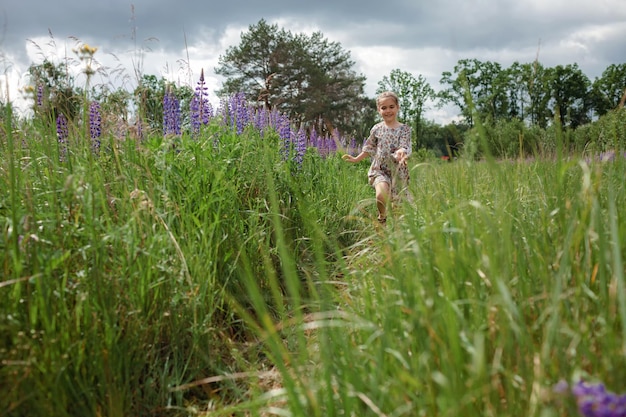 La bambina corre tra i lupini viola nel campo fiorito salute natura estate infanzia felice