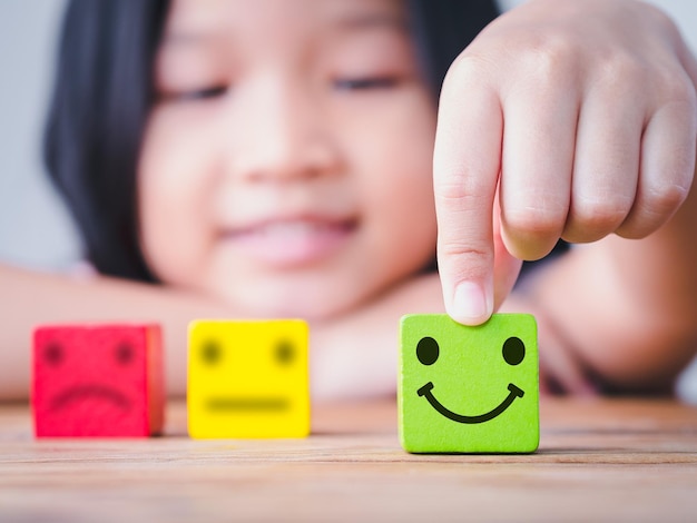 La bambina della piccola Asia sceglie l'icona della faccina sorridente neutra sfocata e triste o infelice