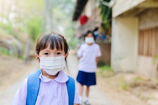 La bambina della scuola ha la maschera per proteggersi dal virus Corona COVID-19 quando il bambino va a scuola
