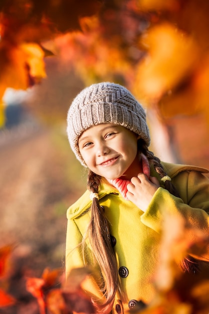 La bambina di 5 anni con le foglie di acero di autunno ride