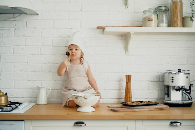 La bambina di cucina mangia caramelle e biscotti da dessert Un'attività interessante