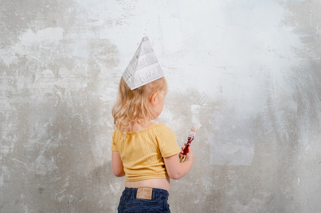 la bambina dipinge il muro di bianco nella nuova casa Ristrutturazione familiare nell'appartamento della casa