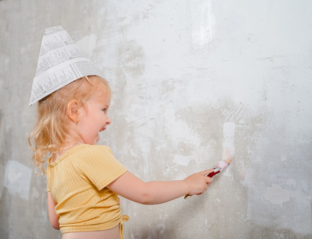 la bambina dipinge il muro di bianco nella nuova casa Ristrutturazione familiare nell'appartamento della casa