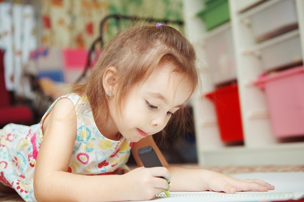 La bambina disegna con attenzione l'immagine nel taccuino con il pennarello