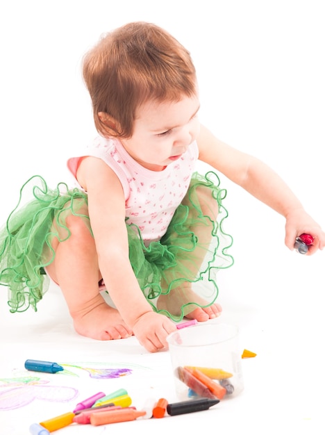 La bambina disegna con i pastelli a cera sulla carta