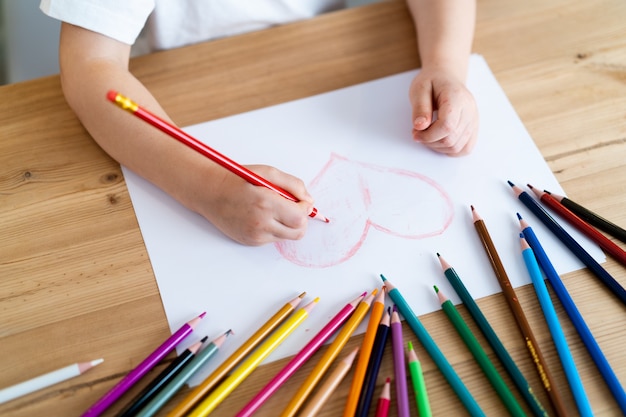 La bambina disegna un cuore rosso