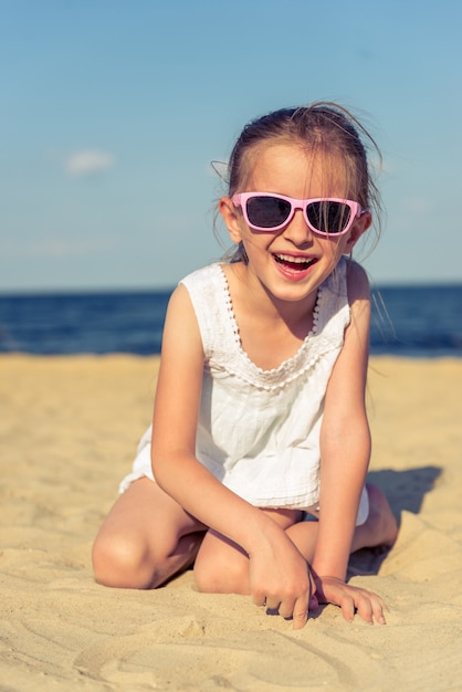 La bambina divertente in occhiali da sole sta esaminando la macchina fotografica.