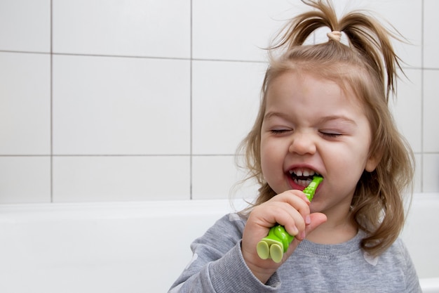 La bambina divertente si lava i denti in bagno. Concetto di cure odontoiatriche