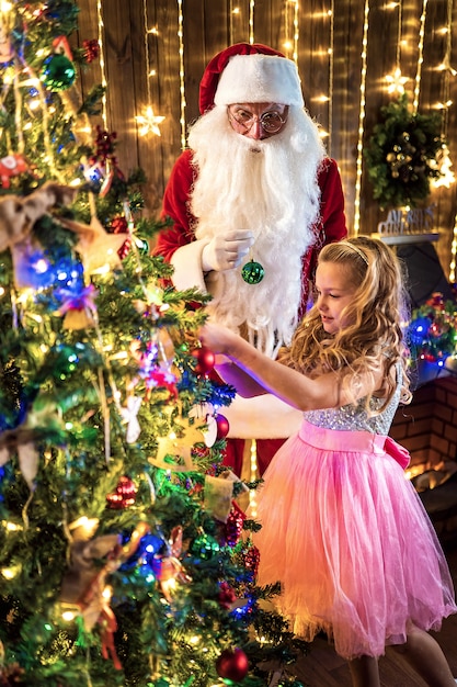 La bambina e Santa decorano l'albero di Natale