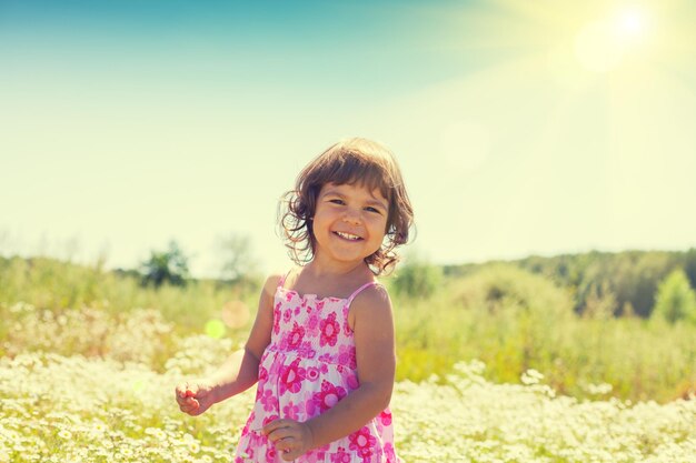La bambina felice cammina sul giacimento di fiore