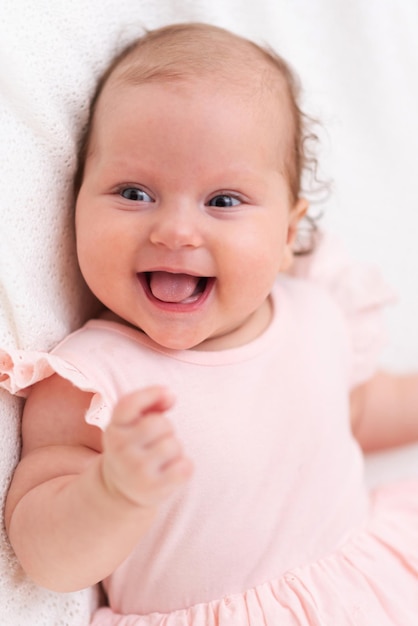 La bambina felice e carina giace su un lenzuolo bianco e coperta con un panno di lana