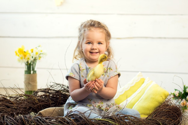 La bambina felice è giocata con simpatici anatroccoli soffici di Pasqua.