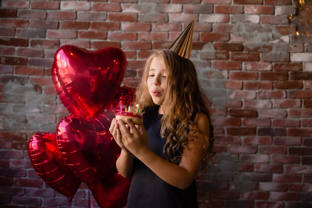 La bambina felice esprime un desiderio e spegne le candeline su una torta