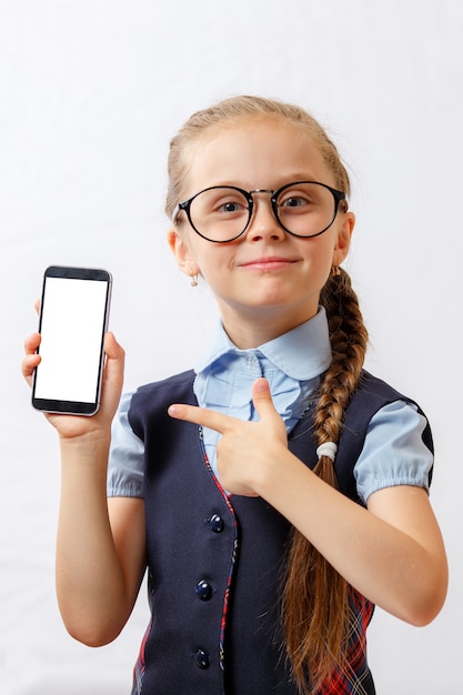 La bambina felice mostra il suo smartphone con lo schermo bianco. modello