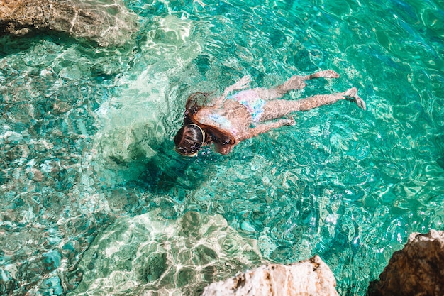 La bambina felice nella maschera dello snorkeling si tuffa underwater con i pesci tropicali