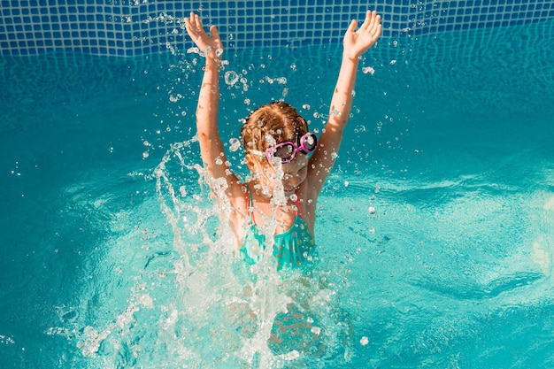 La bambina felice nuota in piscina. vacanze estive. ragazza in costume da bagno e occhiali da nuoto.