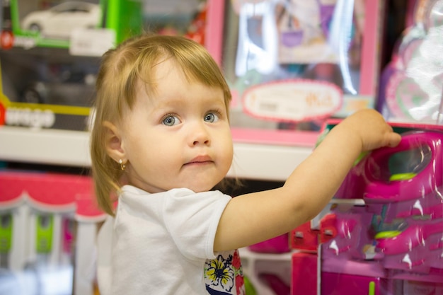 La bambina felice sceglie i giocattoli in un negozio per bambini, teleobiettivo