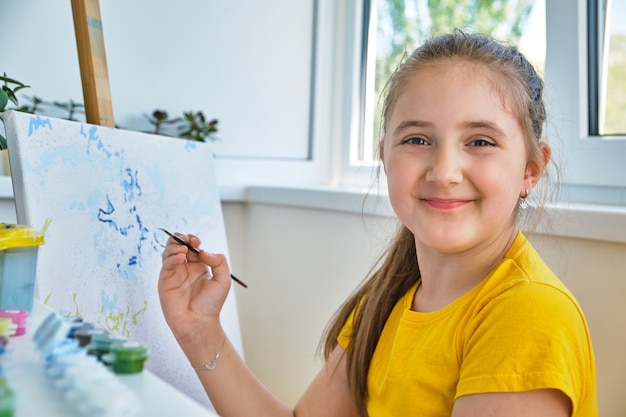 La bambina felice sta dipingendo con la tempera. Bambina felice che dipinge a casa. La ragazza disegna un'immagine in base ai numeri. Primo piano, messa a fuoco selettiva.