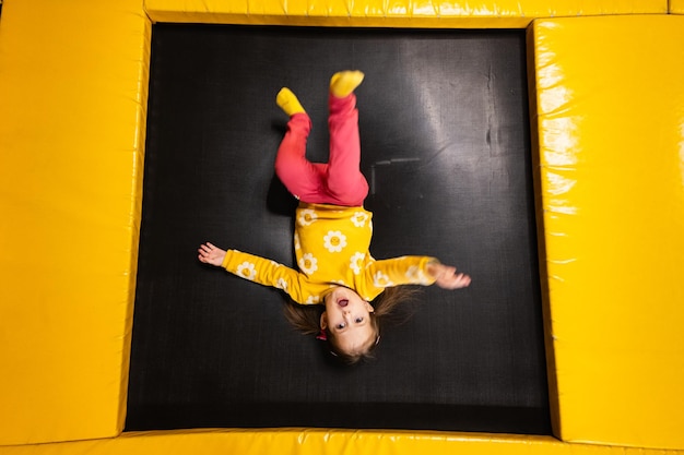 La bambina giace a testa in giù sul trampolino al parco giochi