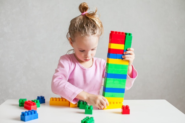 La bambina gioca con il costruttore di plastica multicolore