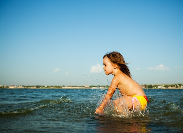 La bambina graziosa piacevole gode dell'acqua di mare calda