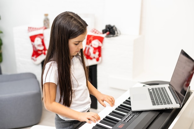 La bambina ha lezione online con l'insegnante su come suonare il pianoforte a Natale