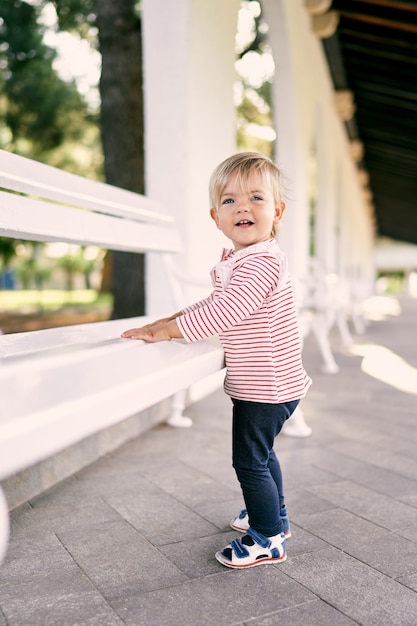 La bambina ha messo le mani su una panchina del padiglione nel parco