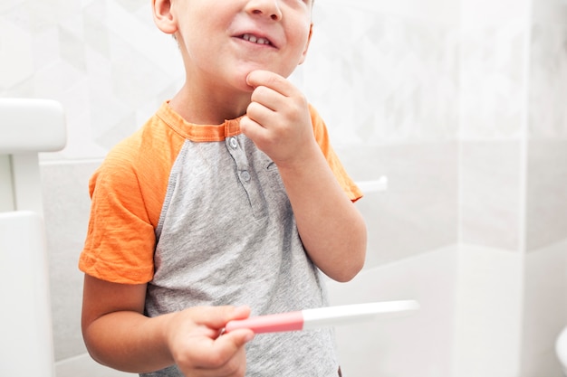 La bambina ha trovato il test di gravidanza positivo e lo guarda e non sa cosa sia.