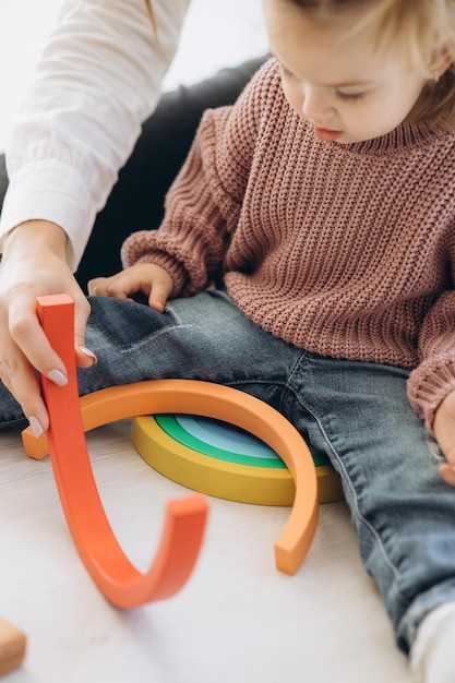 La bambina impara i colori giocando con figure umane colorate di giocattoli cilindrici di legno e mettendole in tazze del colore appropriato Il bambino è felice di aver completato correttamente il compito