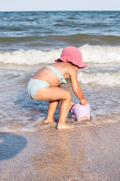 La bambina in costume da bagno si gioca vicino al mare