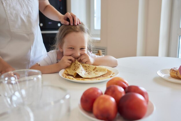 La bambina in cucina mangia le frittelle